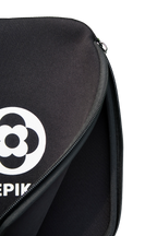 Close-up of a black zippered paddle cover with a white circular logo and partial white text on the left side, shown against a plain white background.