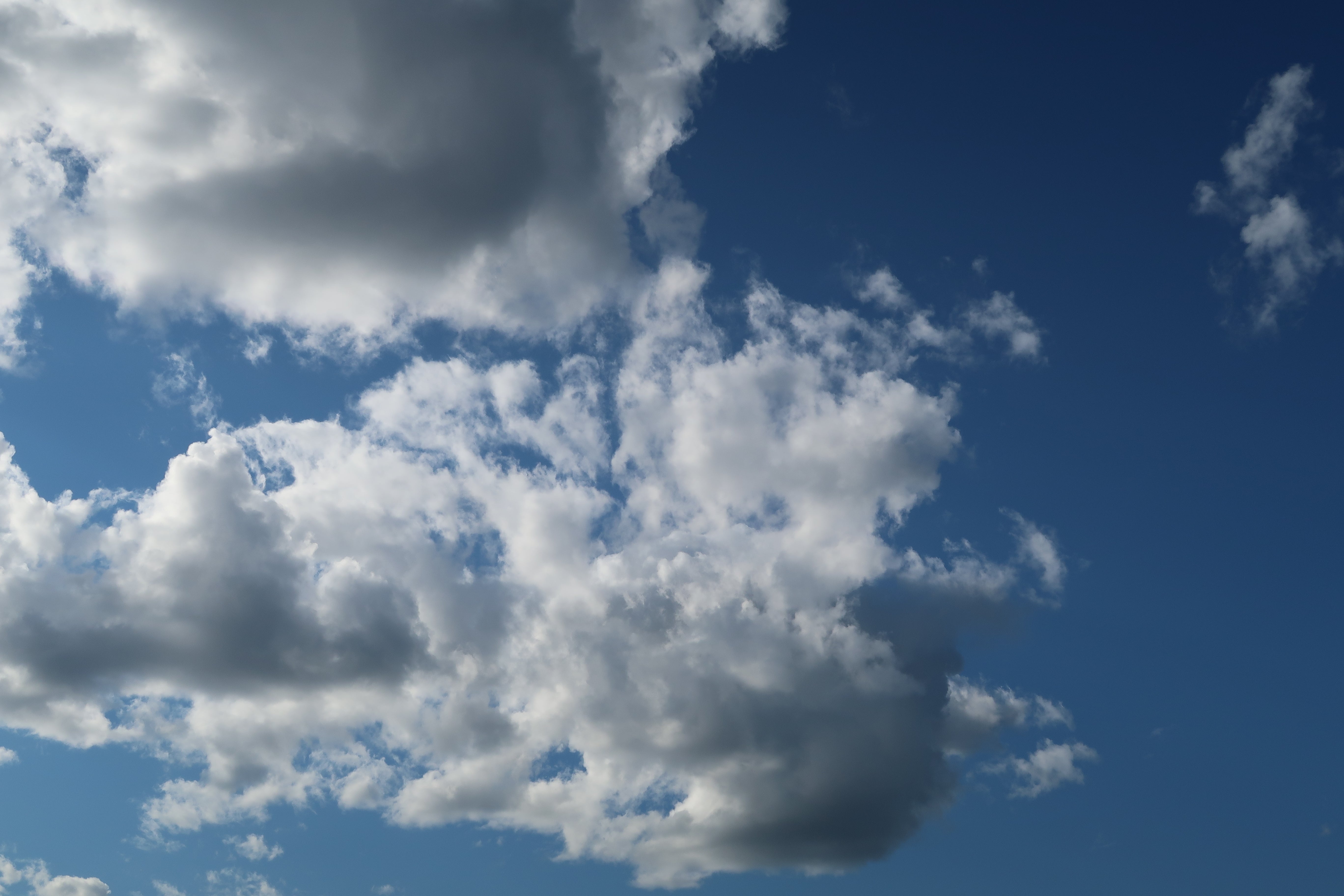 Blue sky with white and gray clouds, photographed from above.